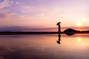 A woman walking along Chichibugahama Beach at sunset