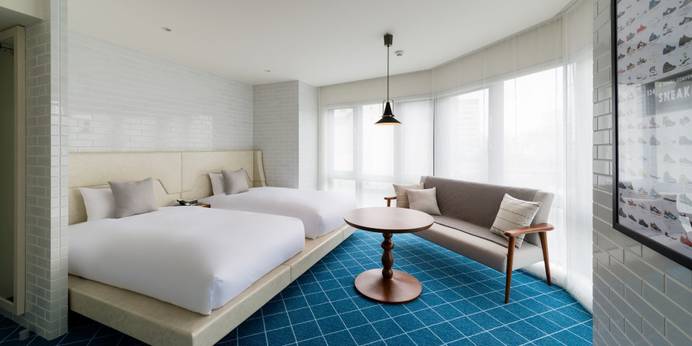 ホテル エディット 横濱（神奈川県 ビジネスホテル）：110cm x 195cmのベッドが2台置かれたコーナーツインルーム一例。おしゃれなソファや壁のアートがアクセントに。写真映えも◎。
●定員1～2名(31㎡)
●おすすめのシーン／カップル旅、ホテル女子会 / 1