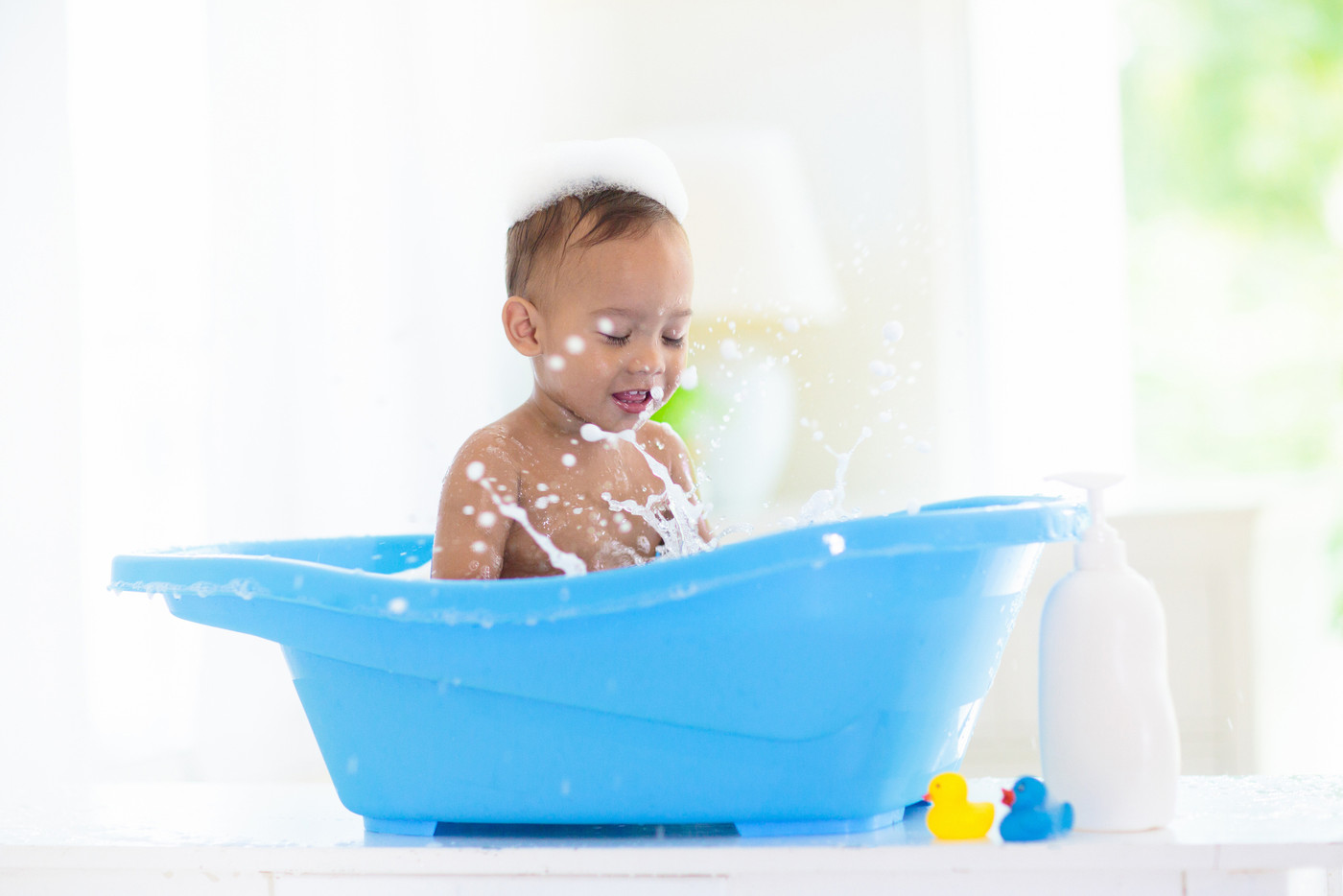 Baby boy in bath. Mother washing infant child.