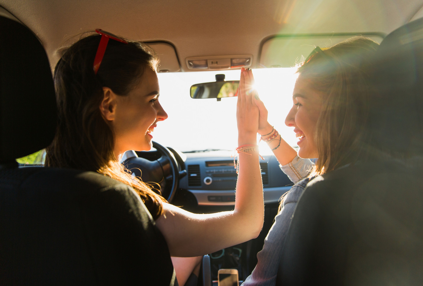 happy teenage girls or women driving in car