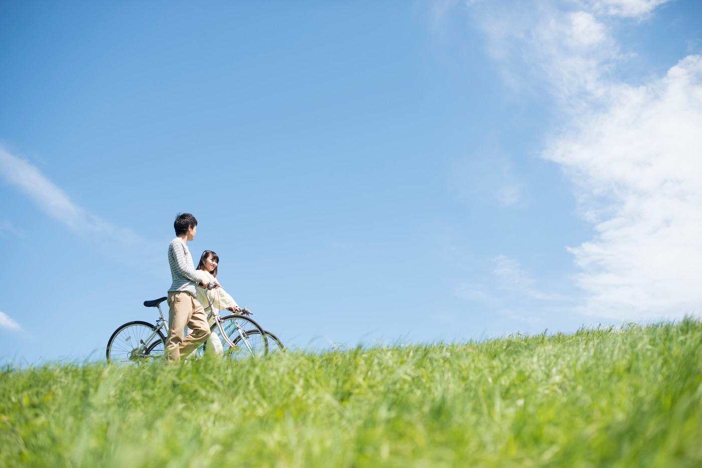 草原で自転車を押すカップル