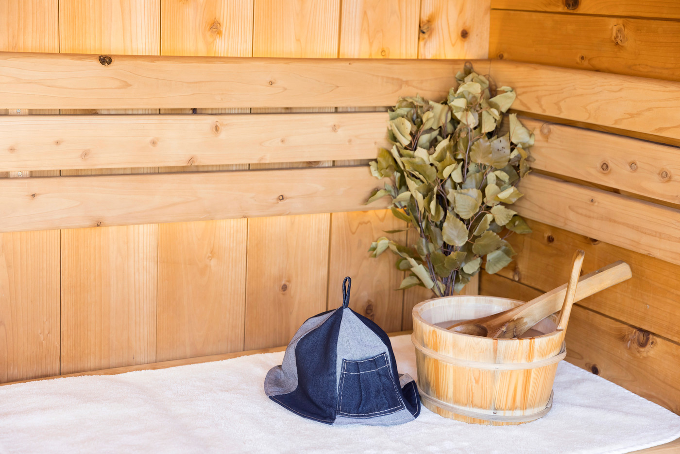 サウナに置かれたサウナ桶とヴィヒタとサウナハット　サウナアイテムイメージ