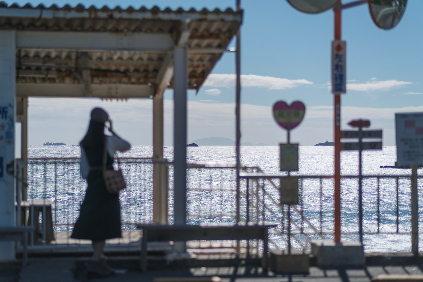 バス停から海を眺める女性（静岡県 伊豆 龍宮窟）