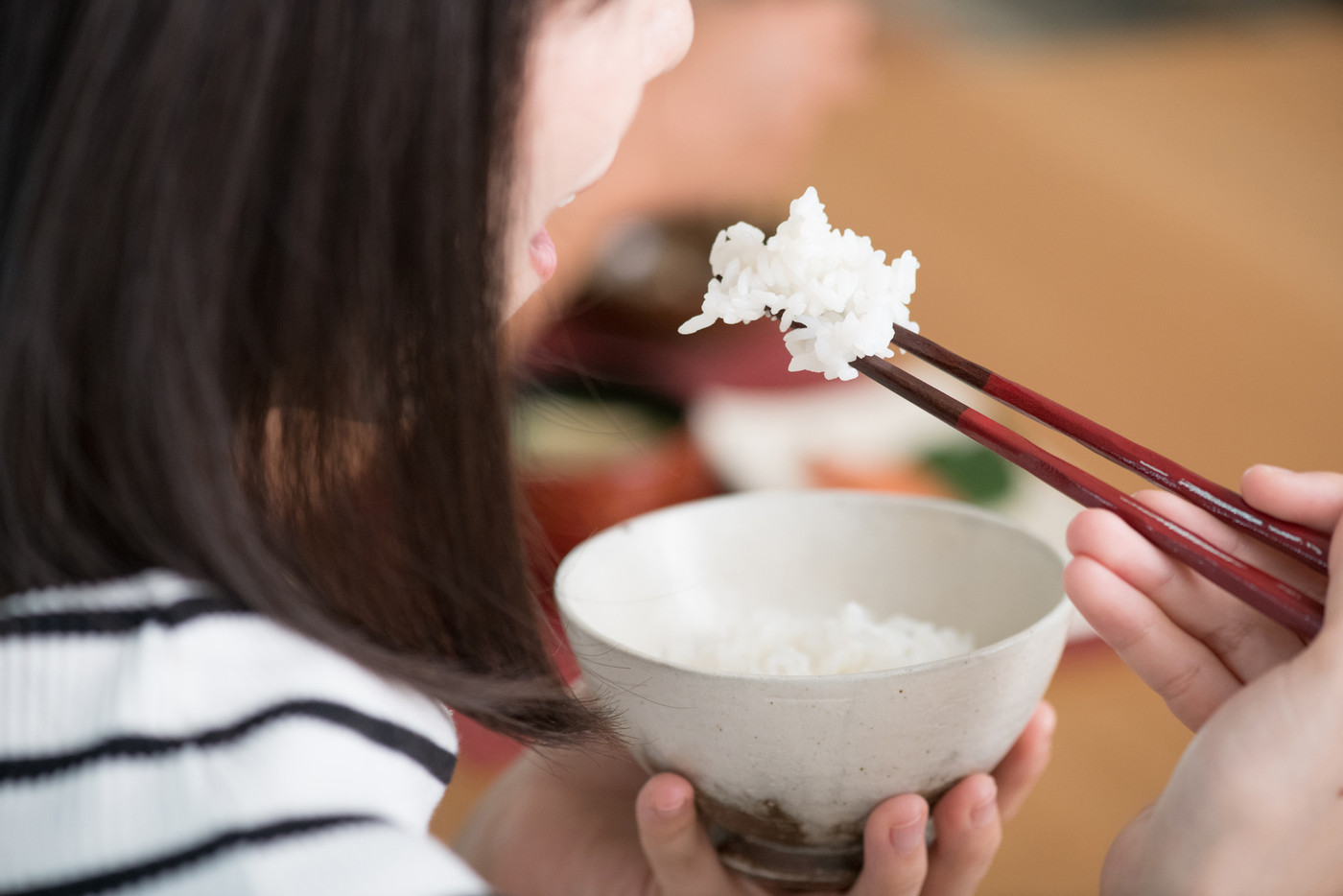 箸でごはんを食べる若い日本人女性