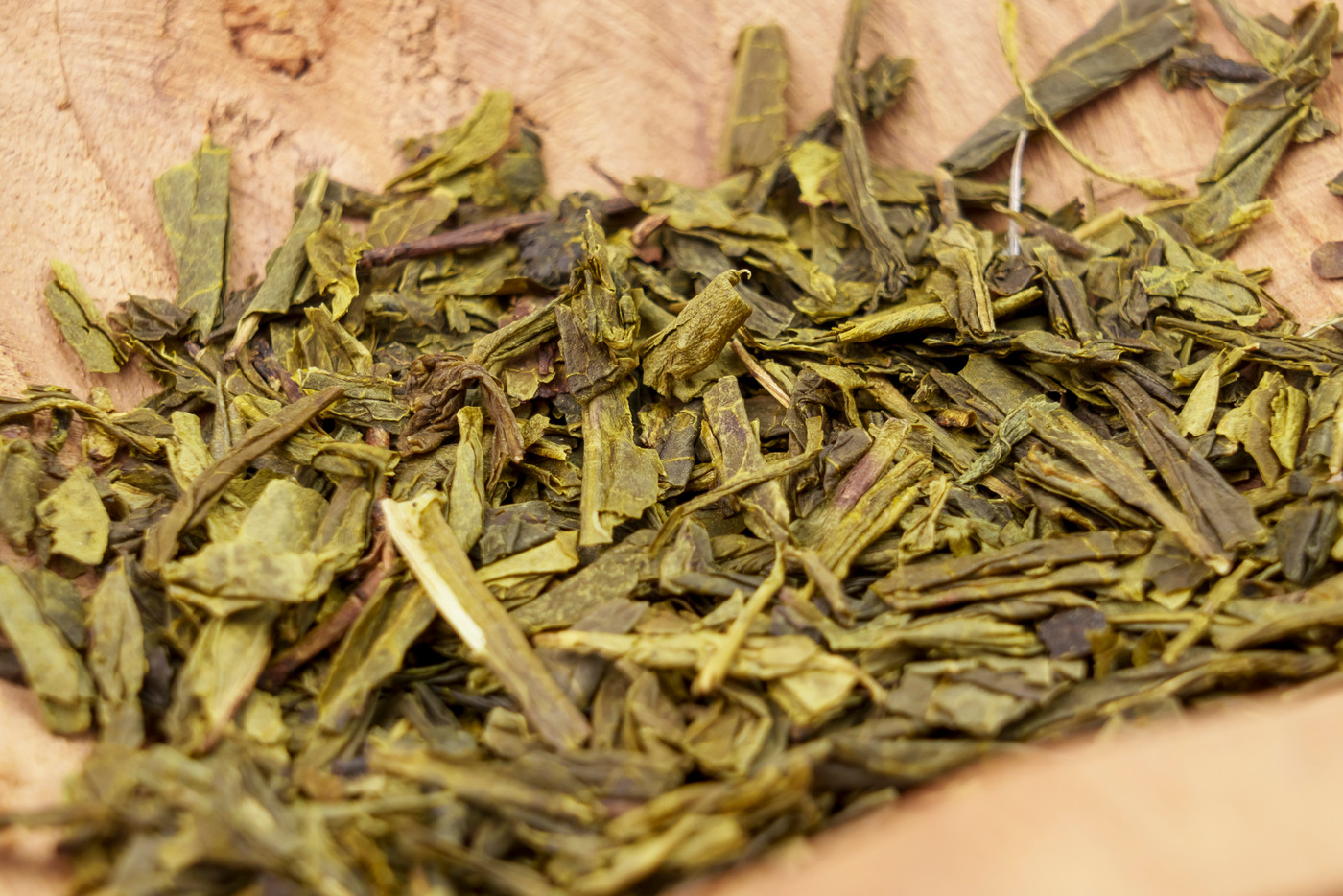 Dry japanese sencha green tea leaves in wooden rustic bowl close up