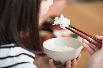 Young Japanese woman eating rice with chopsticks