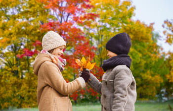 kids with autumn maple leaves over park background