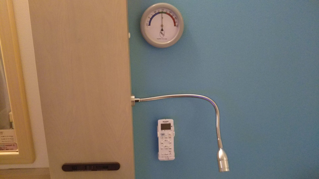 ベッドの横には、温度計、スポットライト、エアコンスイッチ。