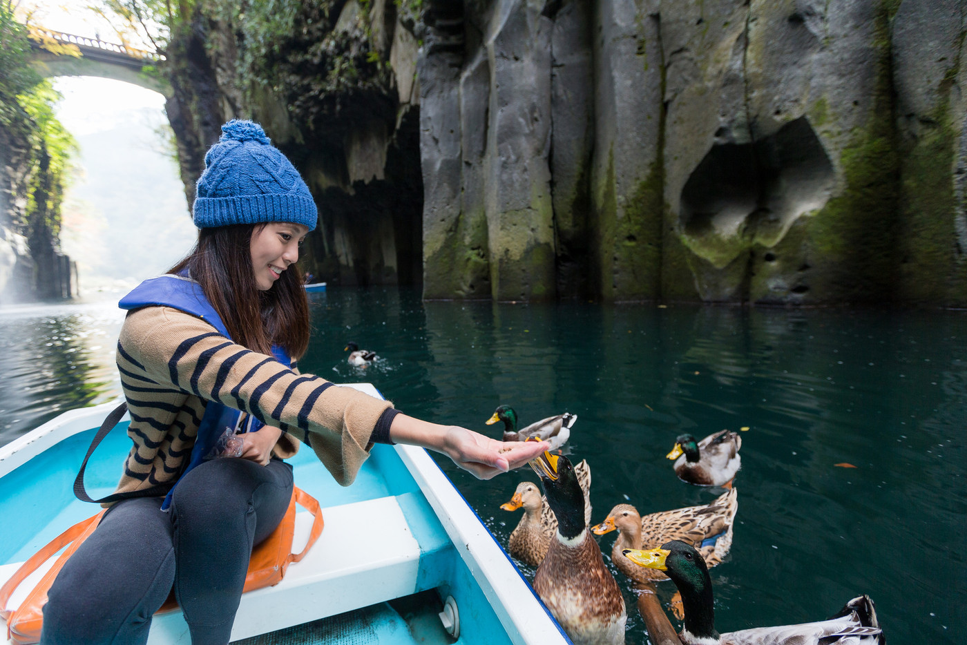Woman feeding duck and travel on boat in Takachiho gorge